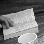A hand opening a paperback book
